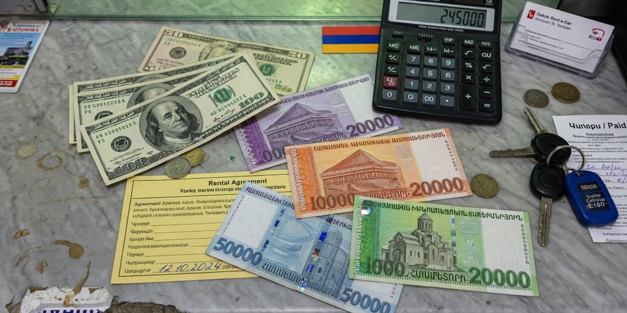 Banknoty dolarów amerykańskich i ormiańskich dramów na ladzie wypożyczalni w Erywaniu