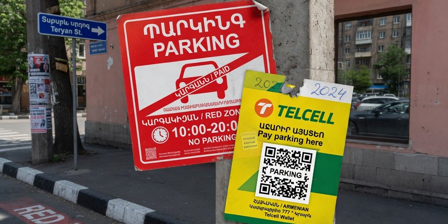 Czerwone oznakowanie strefy płatnego parkowania i naklejka Telcell w centrum Erywania